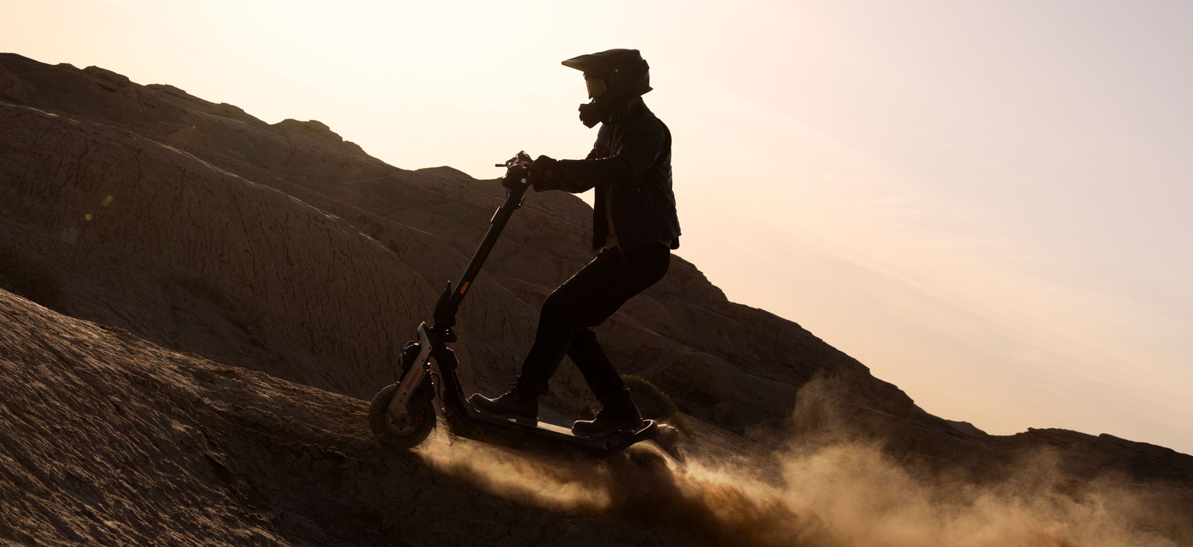 Rider climbing a desert hill on a Segway GT3 Pro at sunset