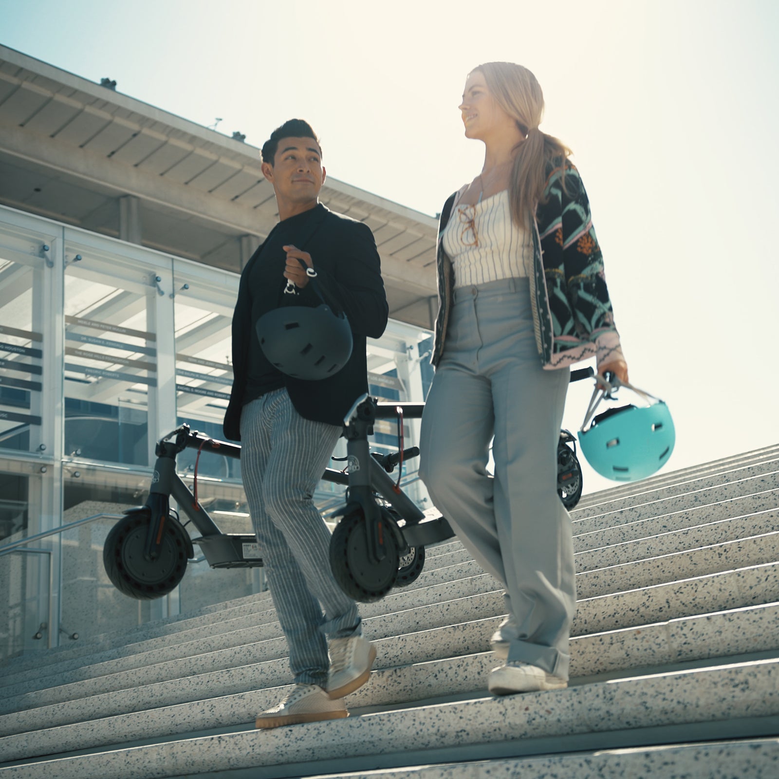 Two riders carrying folded Hiboy S2 scooters down stairs